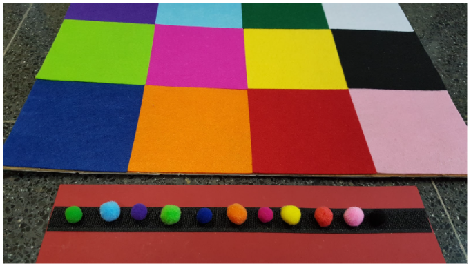 Regleta con 10 pompones de colores que representan la secuencia de celdas que deberá recorrer el robot.