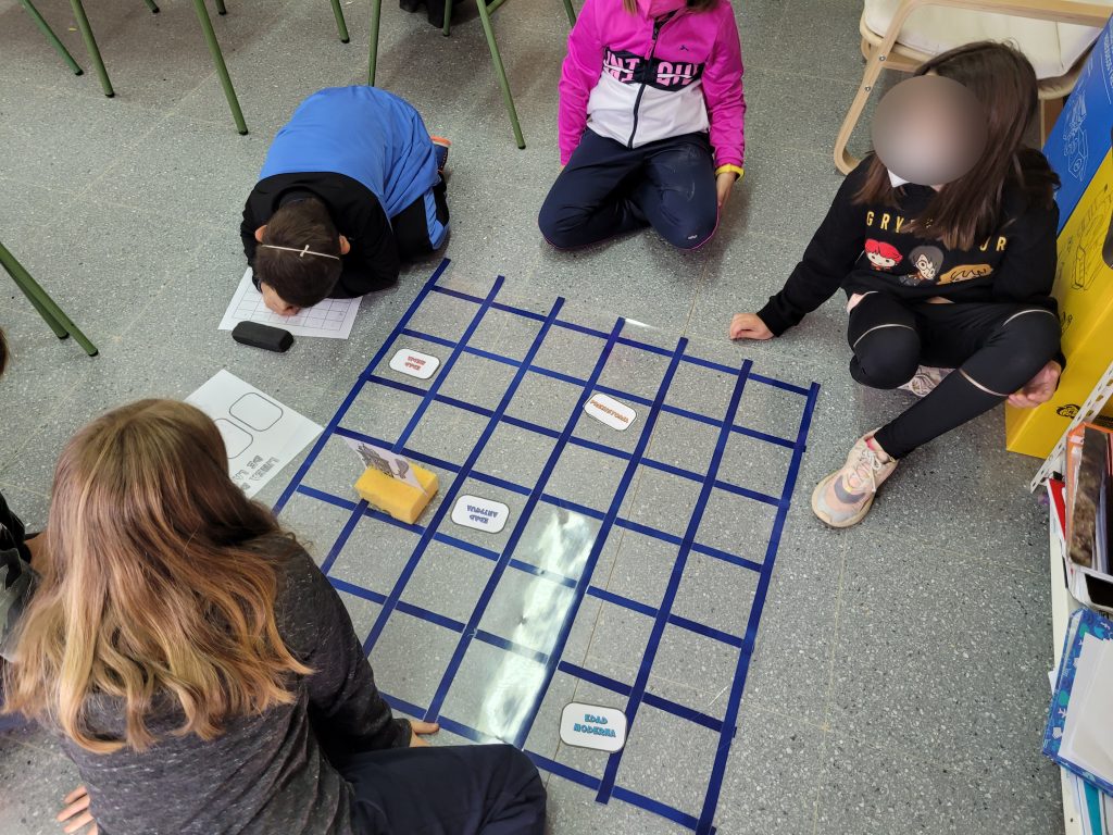 Niños jugando en el suelo con el tablero, personaje y tarjetas