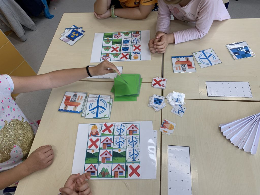 Cuatro niños jugando con dos tableros y una baraja de cartas en medio