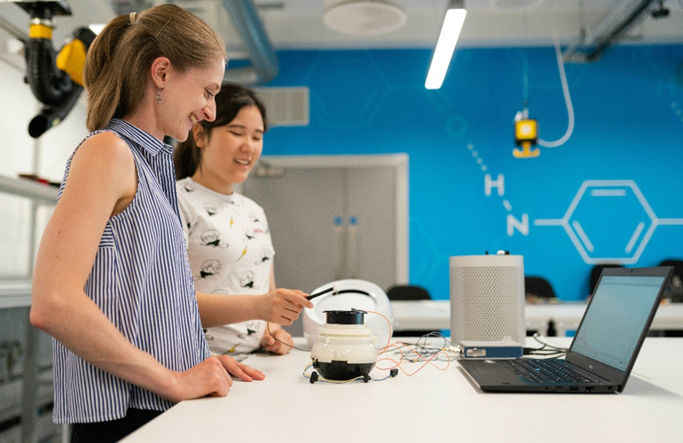 Dos mujeres trabajan en un taller con un sistema de programación y robótica