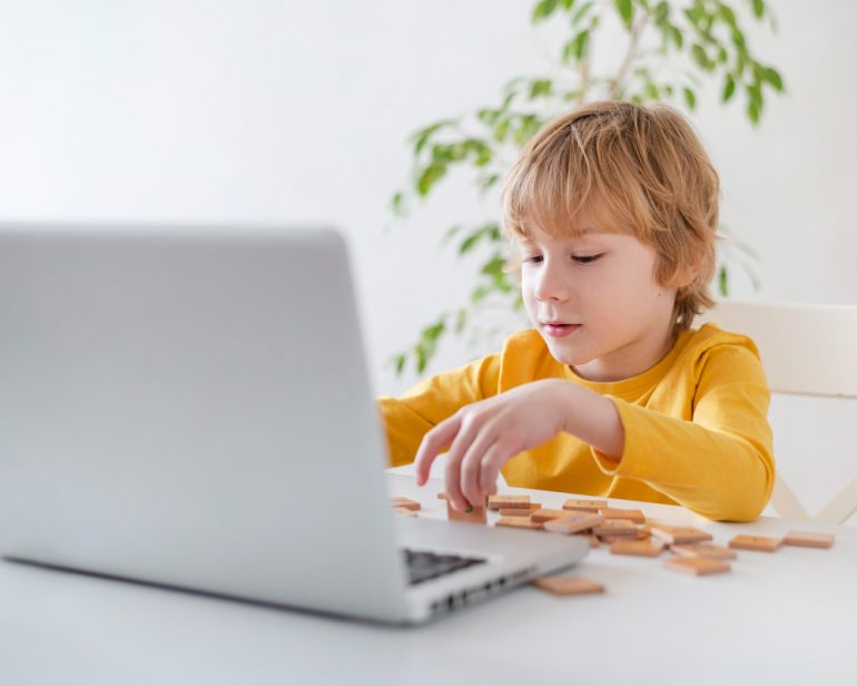 Portada de cabecera para el artículo: El desarrollo del pensamiento computacional en la etapa de Educación Infantil, donde un niño juega con su ordenador