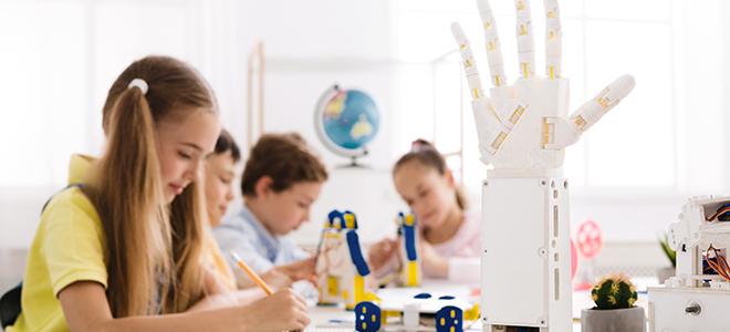 cuatro alumnos en una clase con una mano robótica