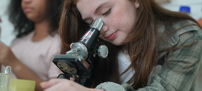 Una niña mirando en un microscopio