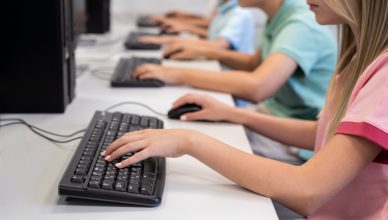 Varios alumnos y alumnas jugando a videojuegos con teclado y ratón en una clase