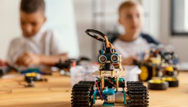Imagen de un pequeño robot, al fondo dos niños con desenfoque