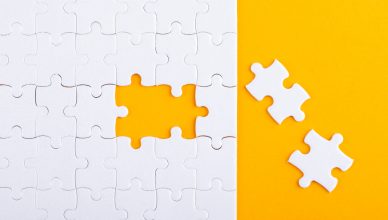 Puzzle al que le faltan dos piezas sobre fondo amarillo