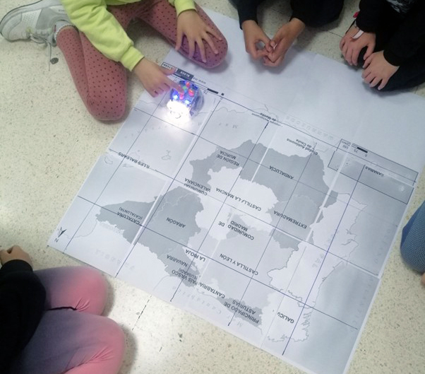 Varios alumnos y alumnas programando un Blue Boot sobre el mapa de España